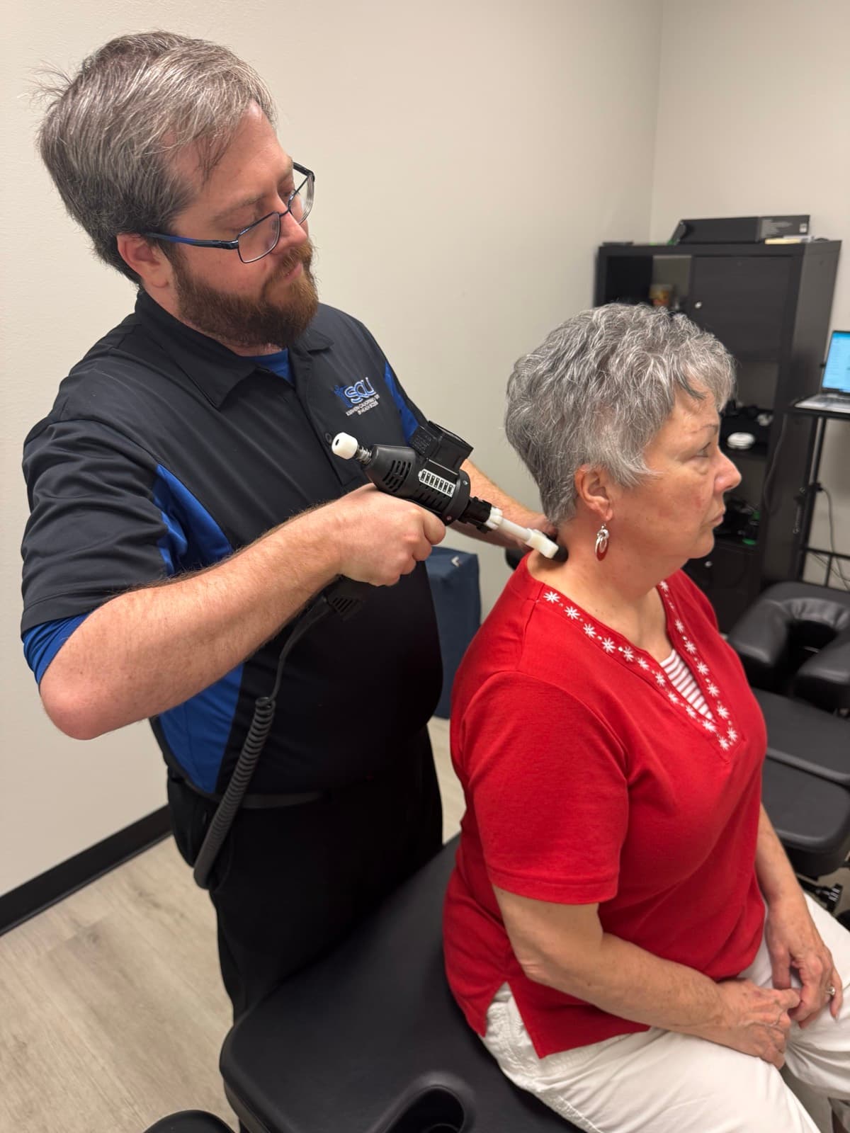 Dr. Smith using percussion therapy on a patient's neck and shoulders at Tailored Touch LV in Henderson, NV